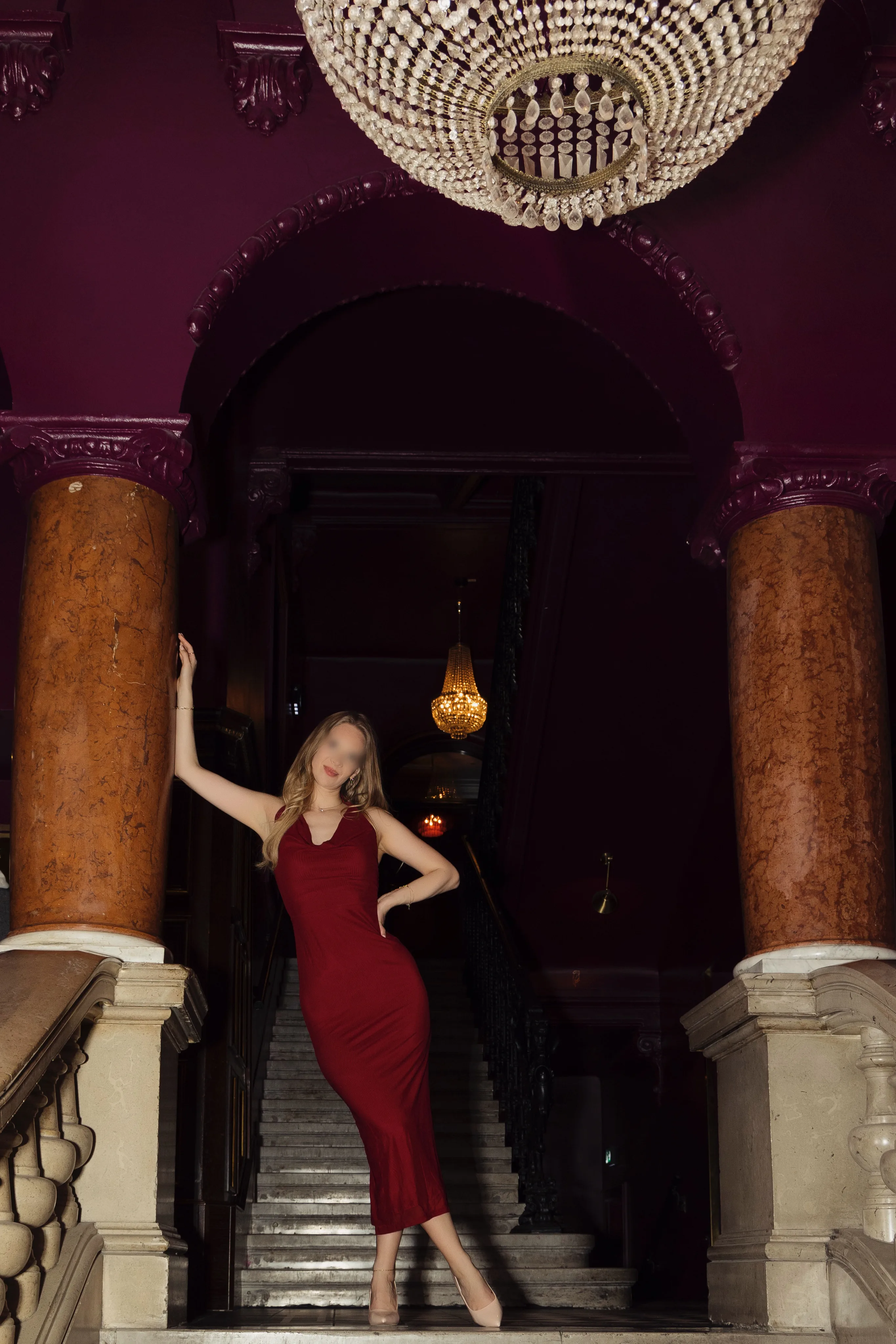 Vixen Mara in red dress posing on luxury hotel staircase - vixen confidence and sensuality